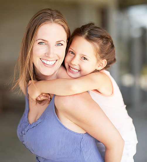 Happy mother smiling with her daughter after successful tooth extraction procedure.