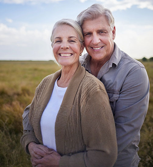 Happy senior couple smiling confidently with natural-looking dental implants.