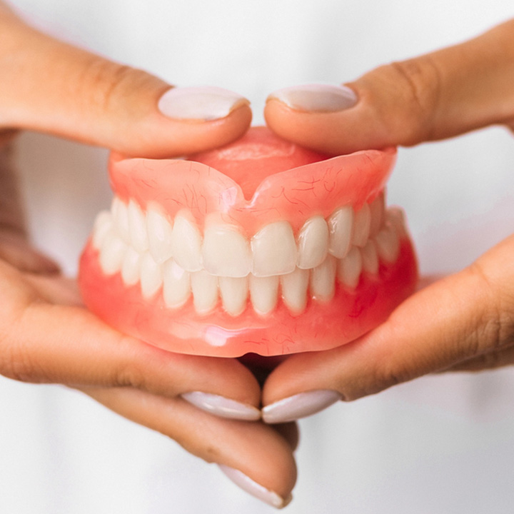 Dentist holding dentures at a dental clinic in Stafford, VA