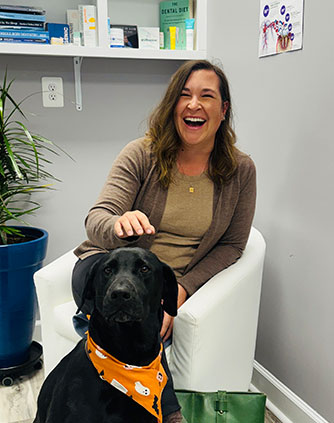 Happy patient smiling with her pet dog sitting calmly beside her in the welcoming waiting area of Karande Dental Care