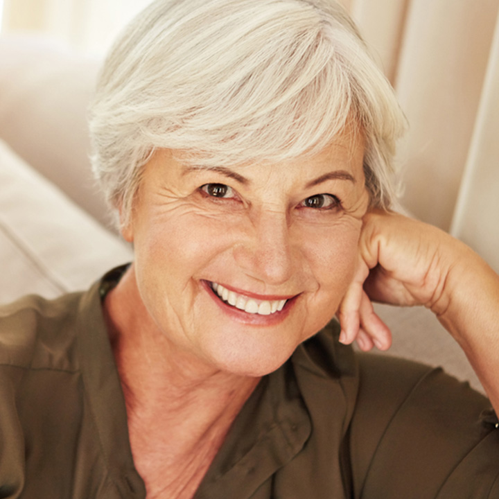 Elderly woman showing improved smile with dentures in Stafford, VA